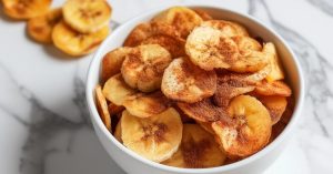 Banana chips on a white bowl garnished with cinnamon powder.