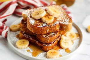 A stack of french toast with banana slices and cinnamon