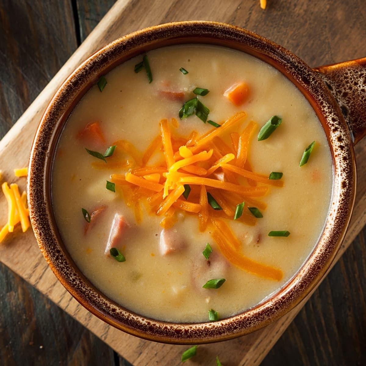 Beer cheese soup with cheddar cheese and chives served on a wooden bowl.