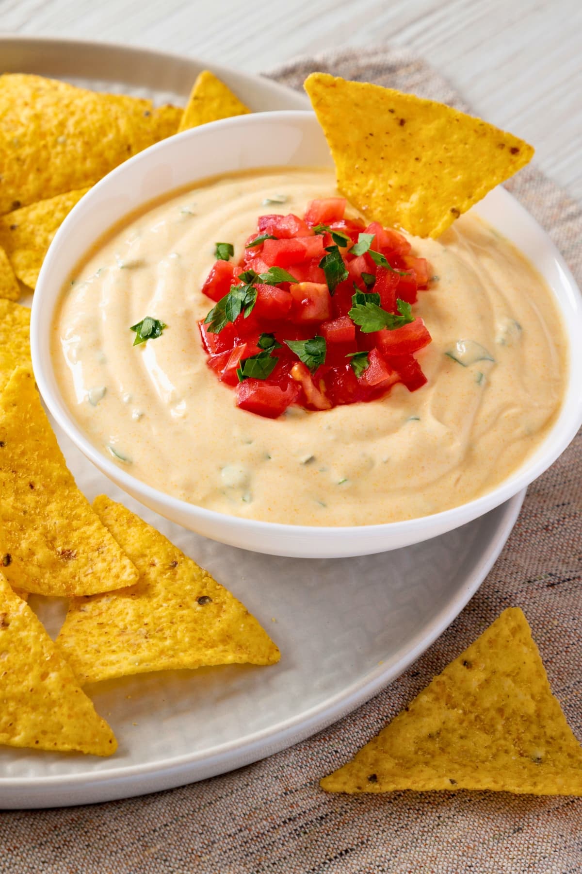 Tortilla chips with white queso dip in a bowl garnished with salsa.