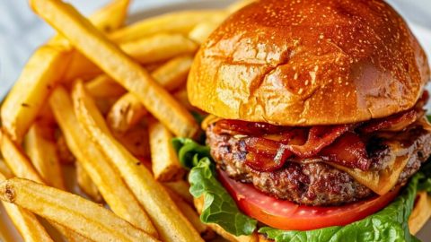 Burger with oven baked potatoes served with fries on a plate.