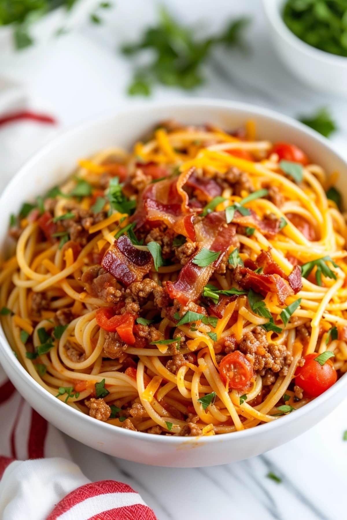 Cowboy spaghetti in a bowl topped with chopped parsley and crispy bacon.
