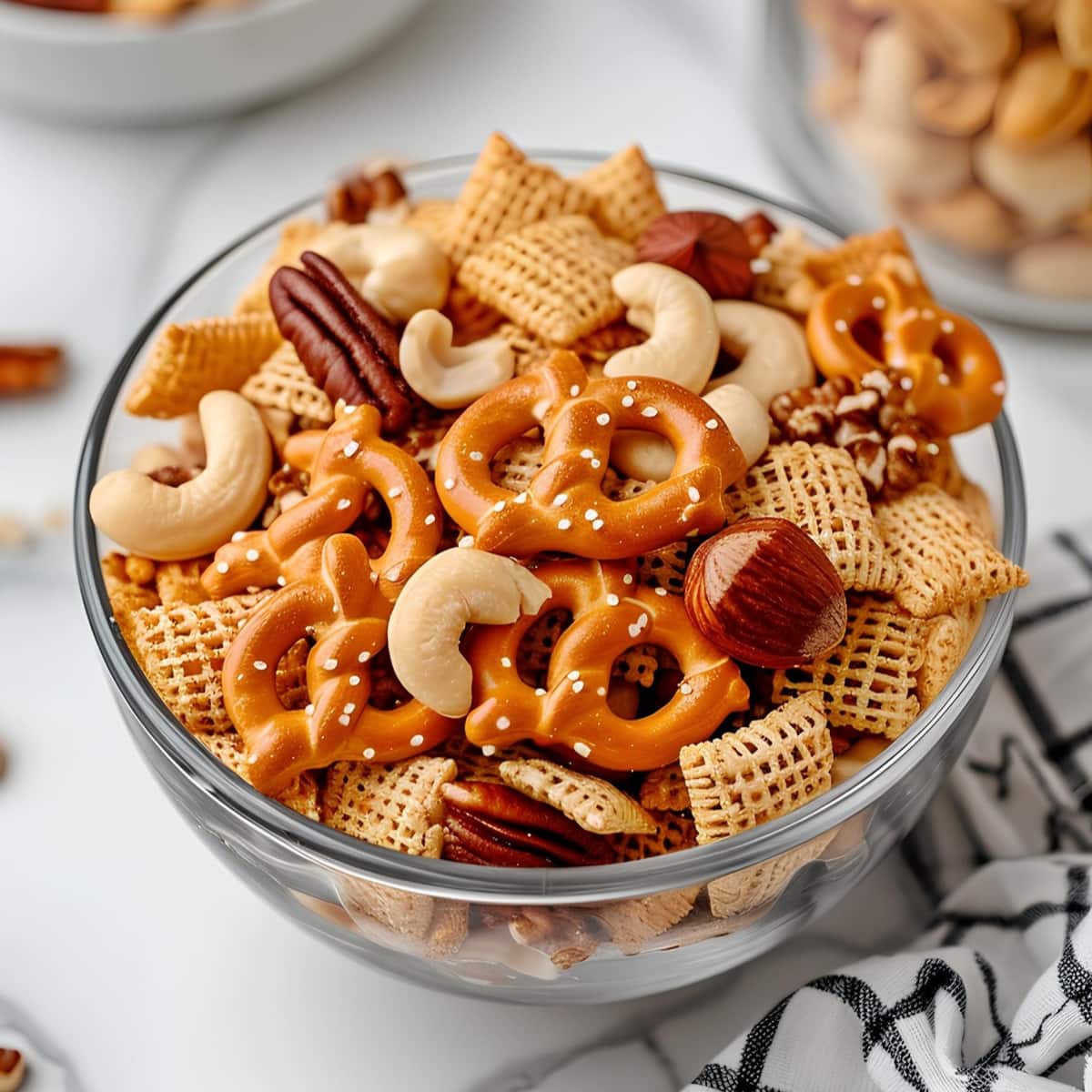 Homemade air fryer chex mix in a glass bowl with nuts and pretzels