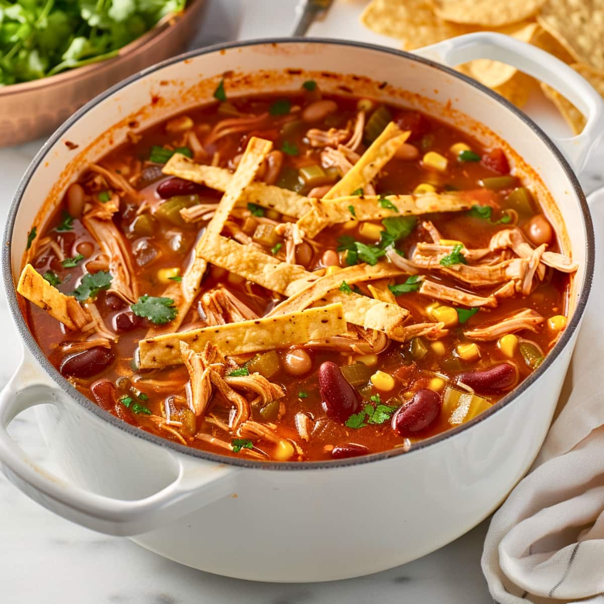 Chicken tortilla soup cooked in a white pot.
