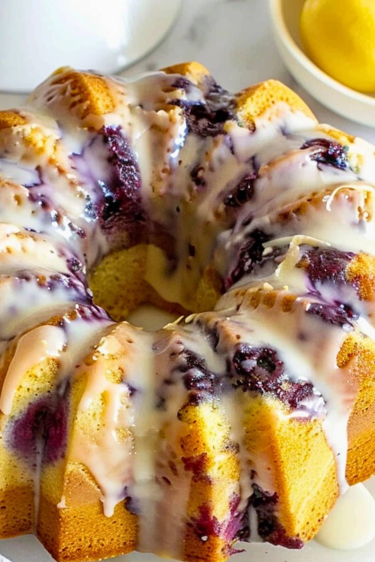 Whole lemon blueberry pound cake with dripping sugar glaze on top.