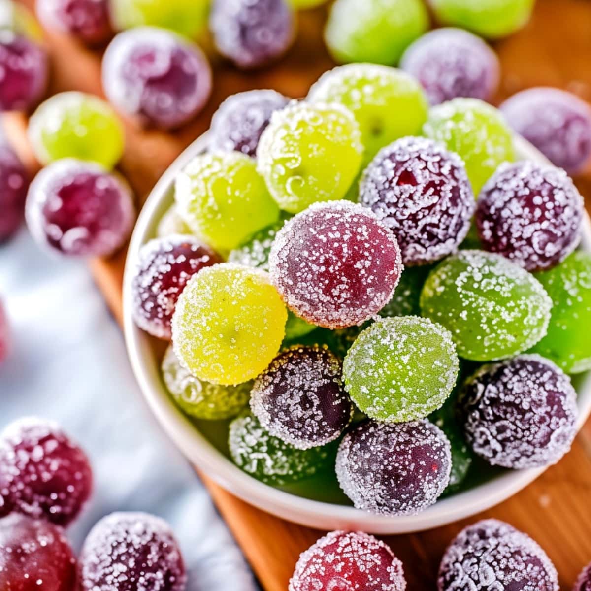Sweet homemade colorful candied grapes in a bowl on a wooden board