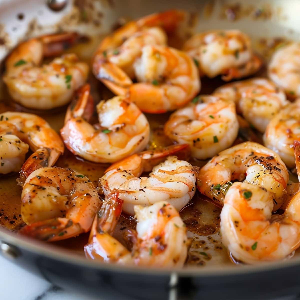 Cooked shrimp in a skillet with sauce and herbs