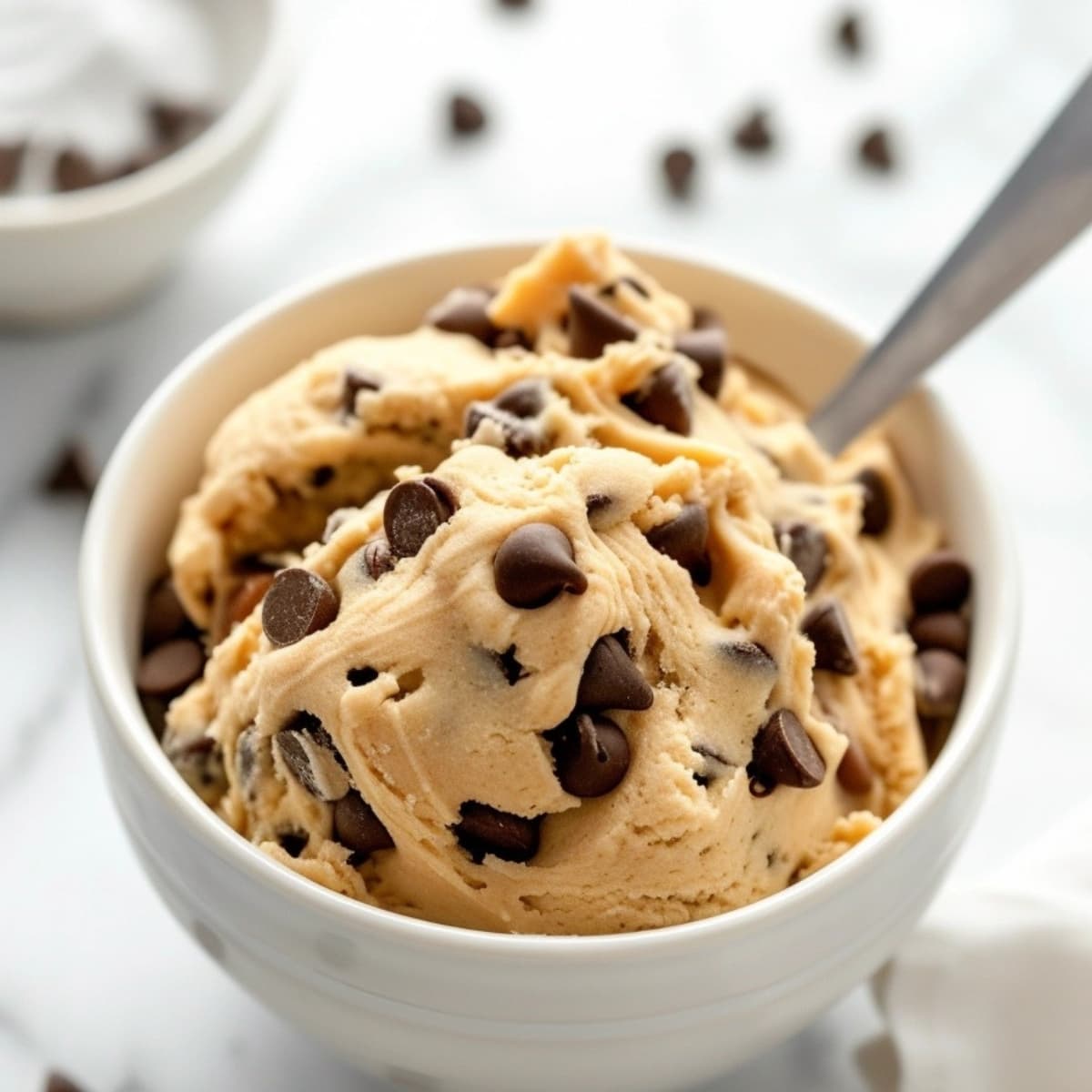 Edible cookie dough with chocolate chips and spoon.