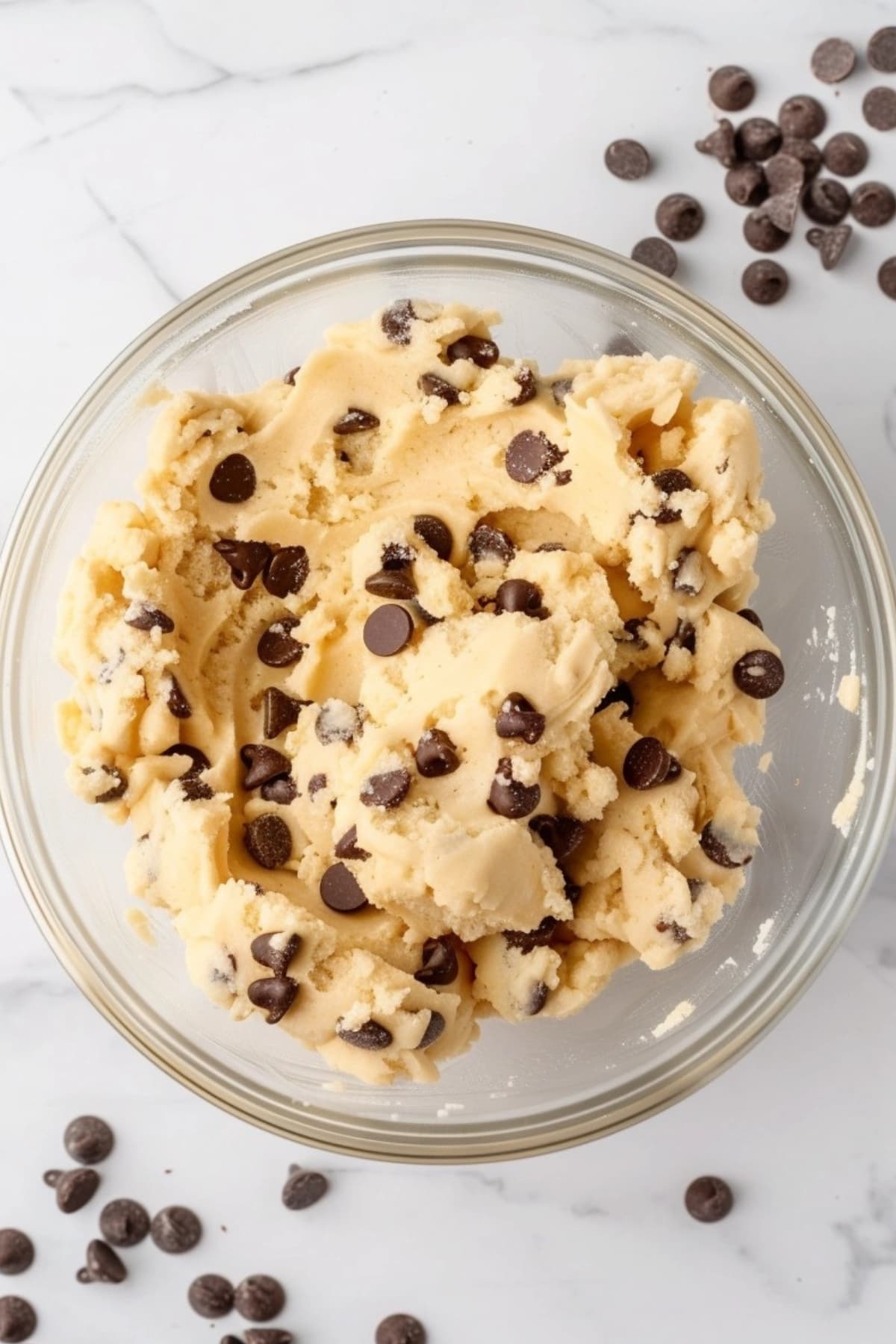 Edible cookie dough with chocolate chips in a glass bowl.