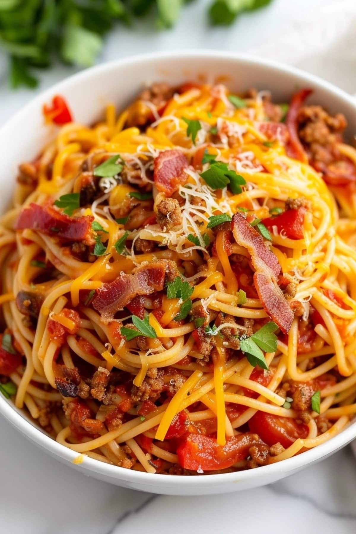 Closeup of a bowl of cowboy spaghetti loaded with chopped bacon.