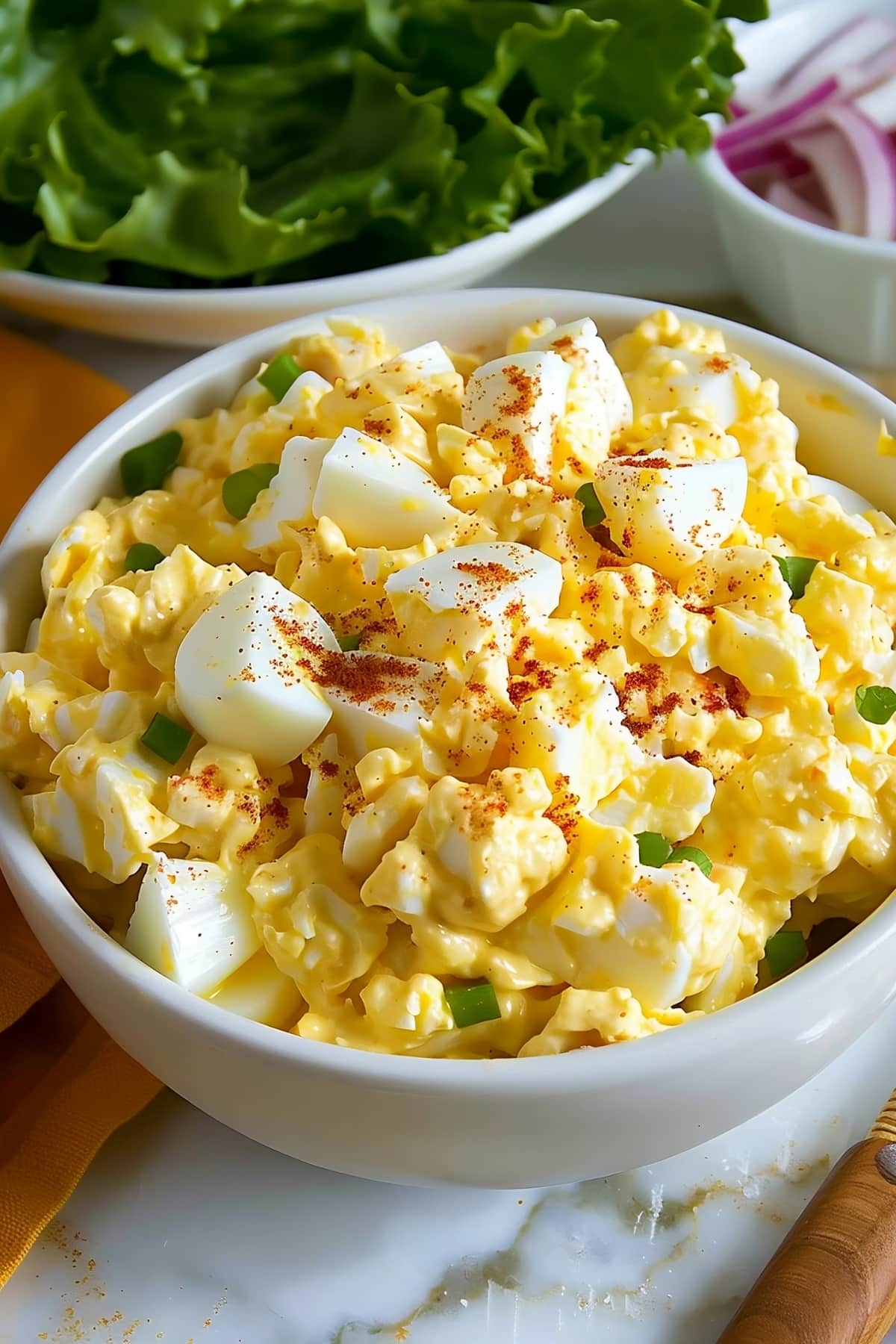 Bowl of creamy homemade egg salad with paprika and chopped green onions