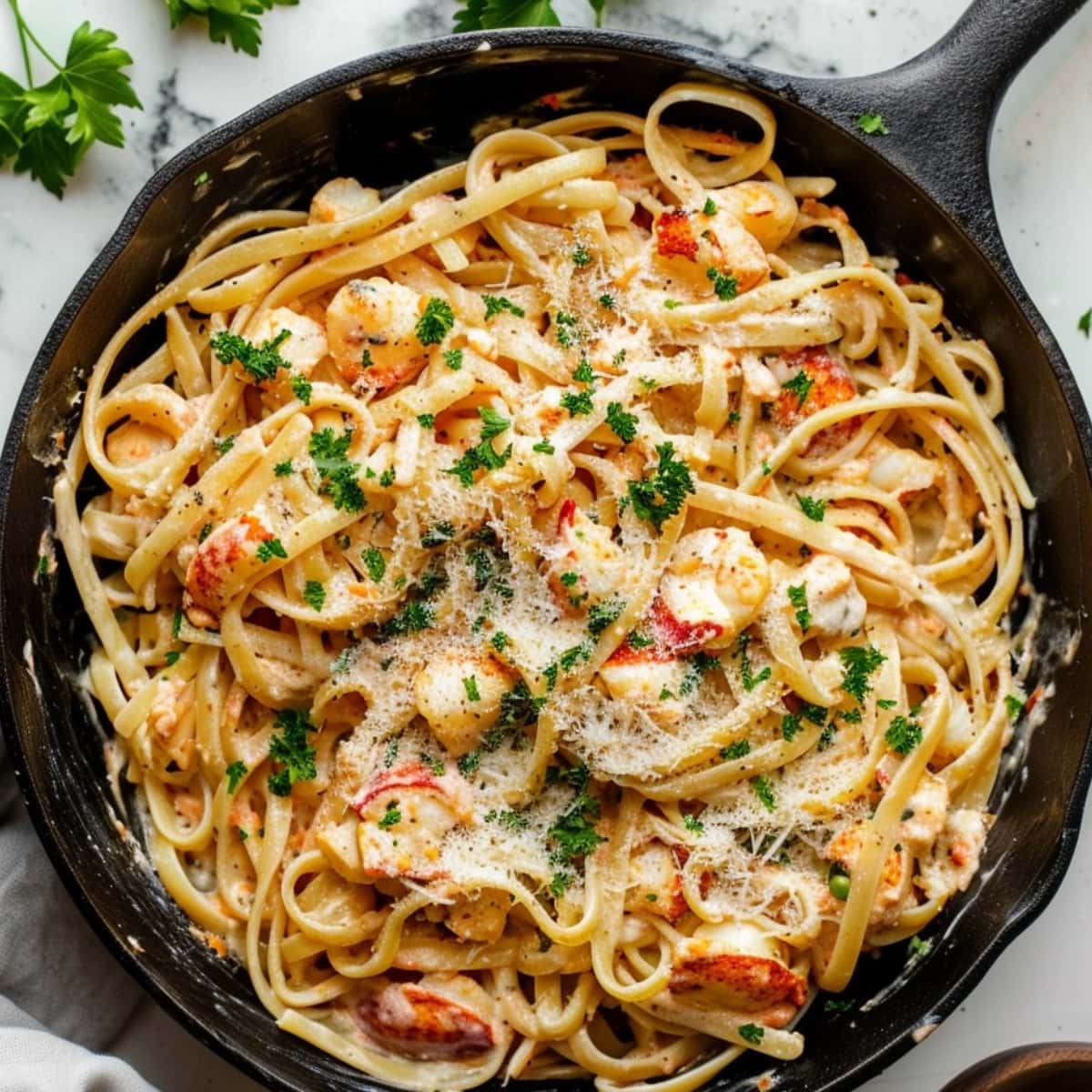 Creamy pasta linguine with lobster in a cast iron skillet.