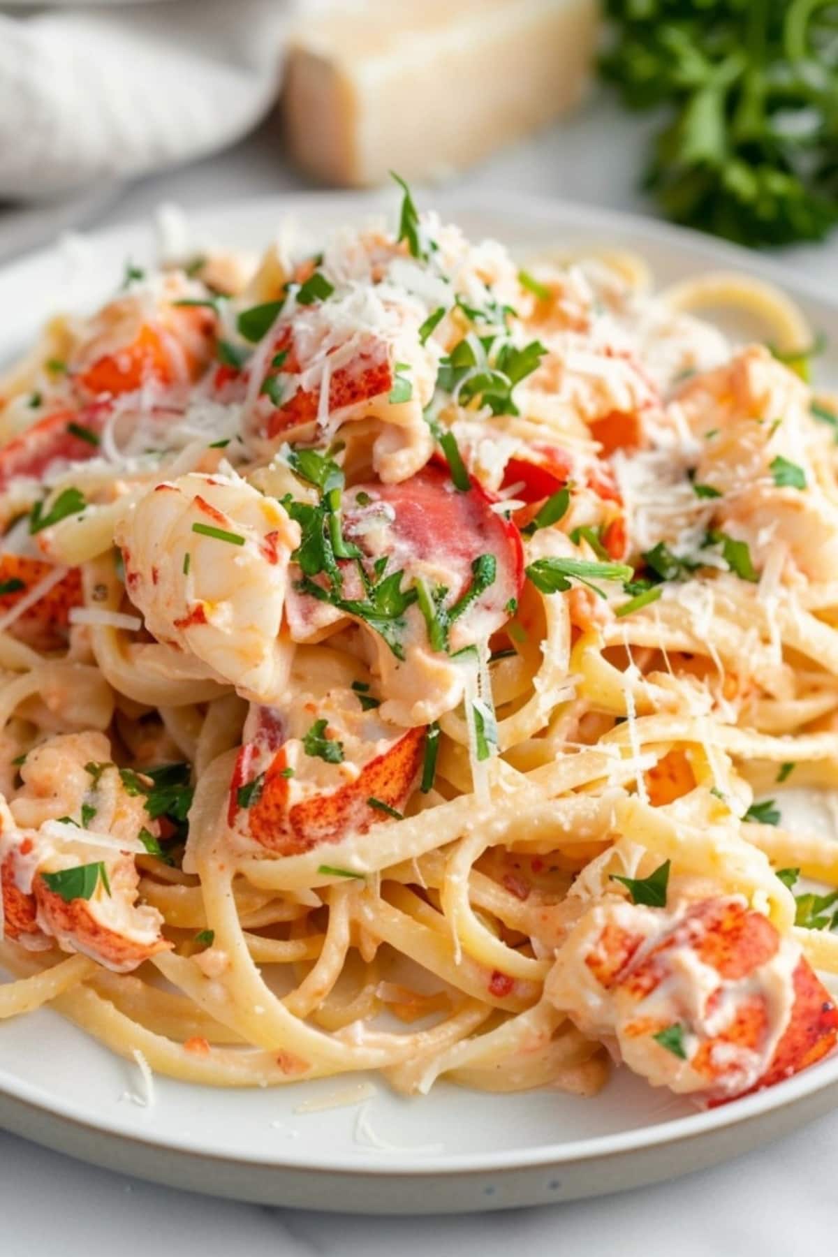 Creamy pasta with lobster on a plate topped with parmesan cheese.