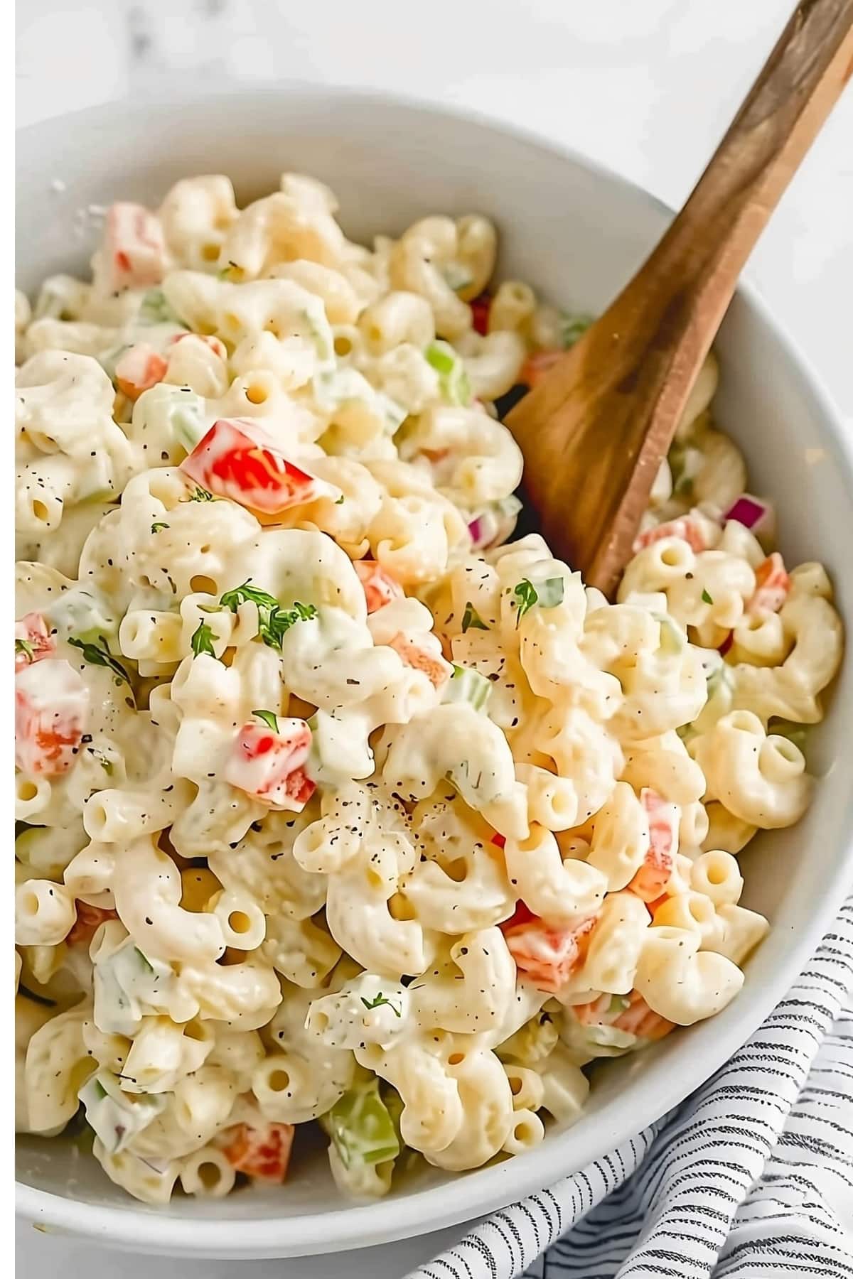 Creamy macaroni salad in a bowl with wooden spoon.