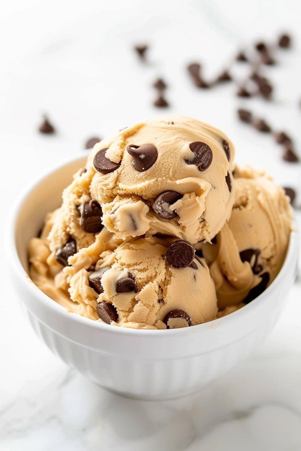 Scoops of edible cookie dough with chocolate chips in a bowl.