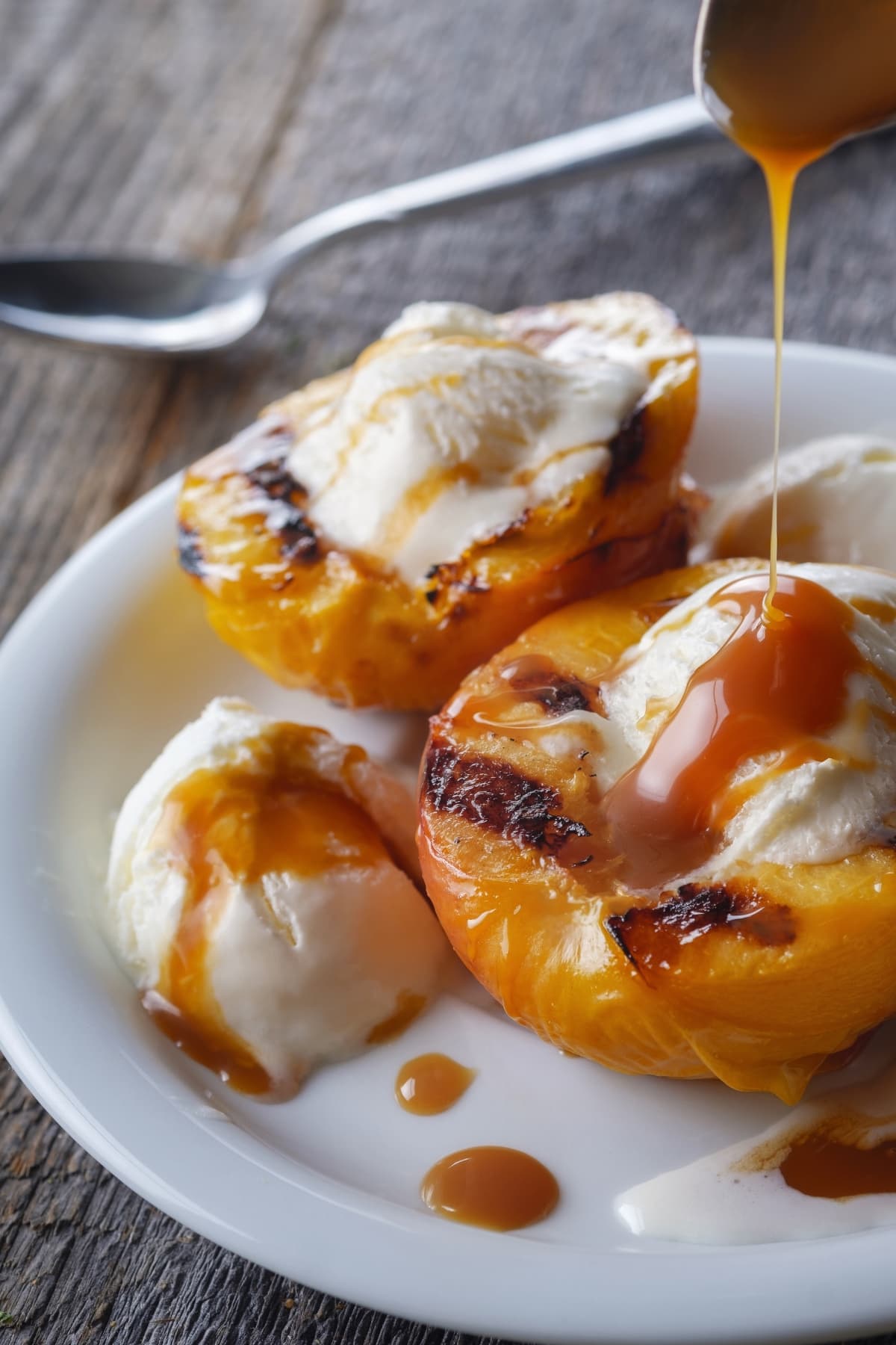 Grilled peaches topped with vanilla ice cream drizzled with caramel syrup.