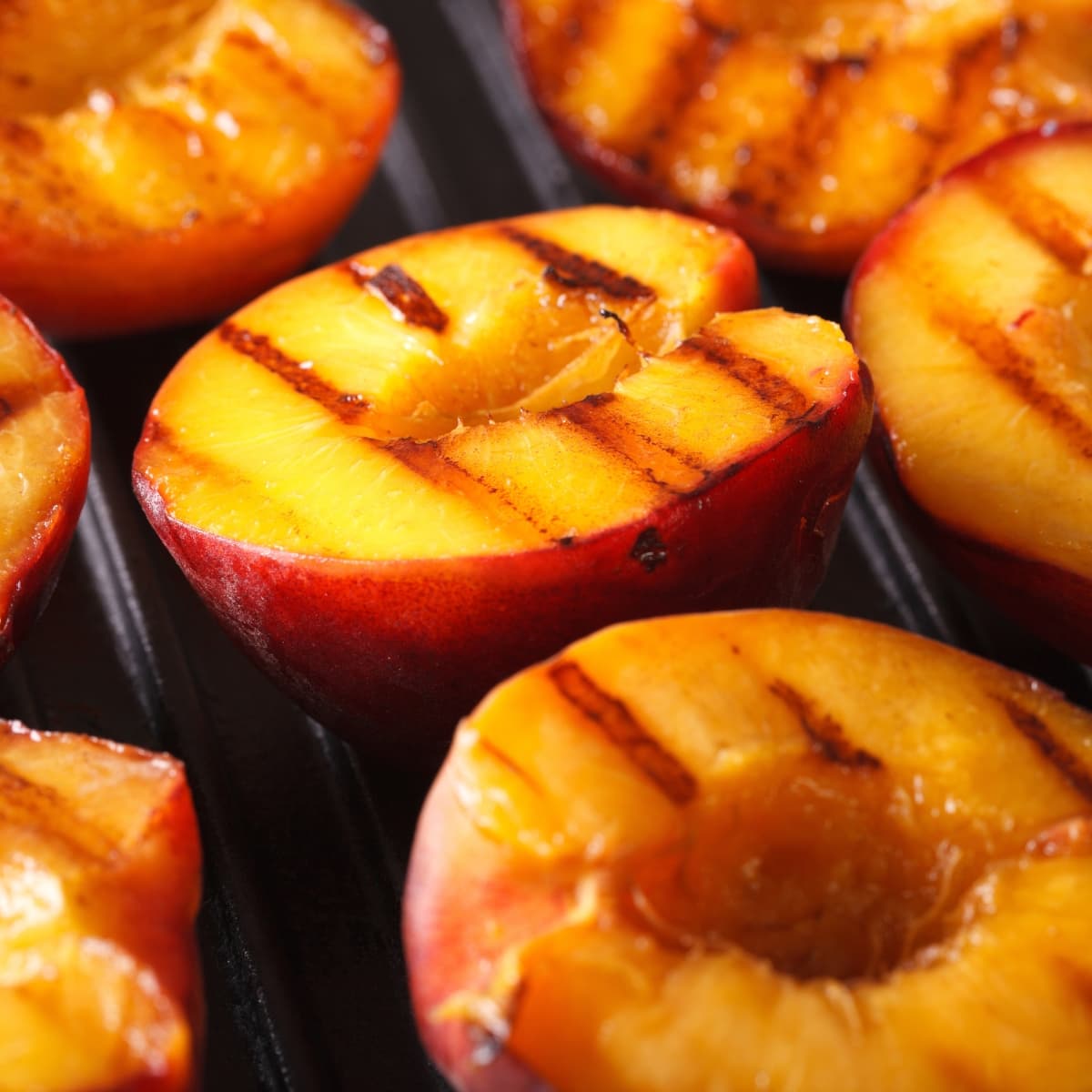 Ripe peaches cut in halves on a grilling pan.