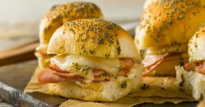 Bunch of sliced ham and cheese sliders.
