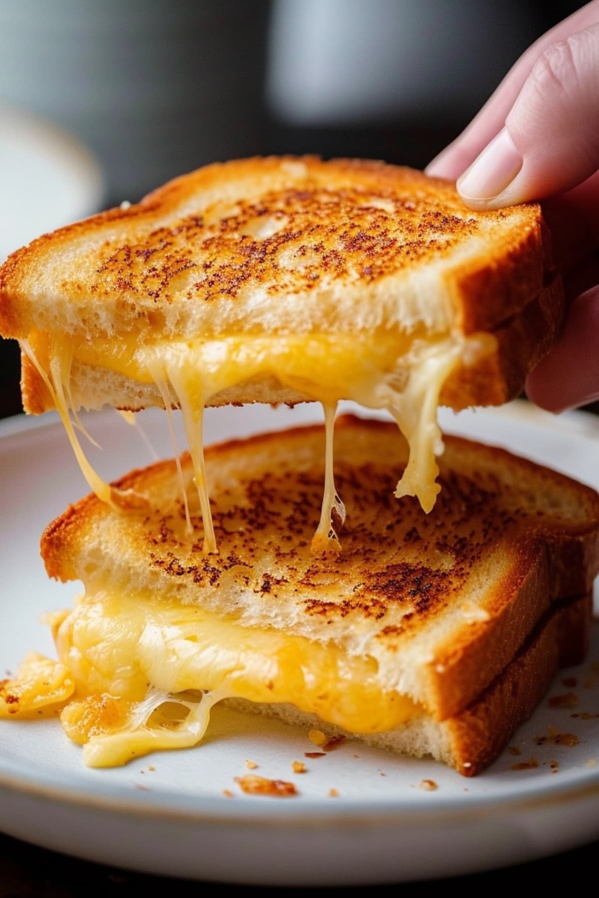 Hand pulling apart grilled cheese sandwich