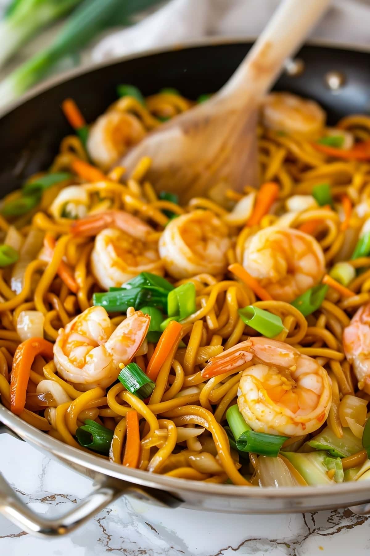 A pan filled with lo mein noodles and shrimp, ready to be served