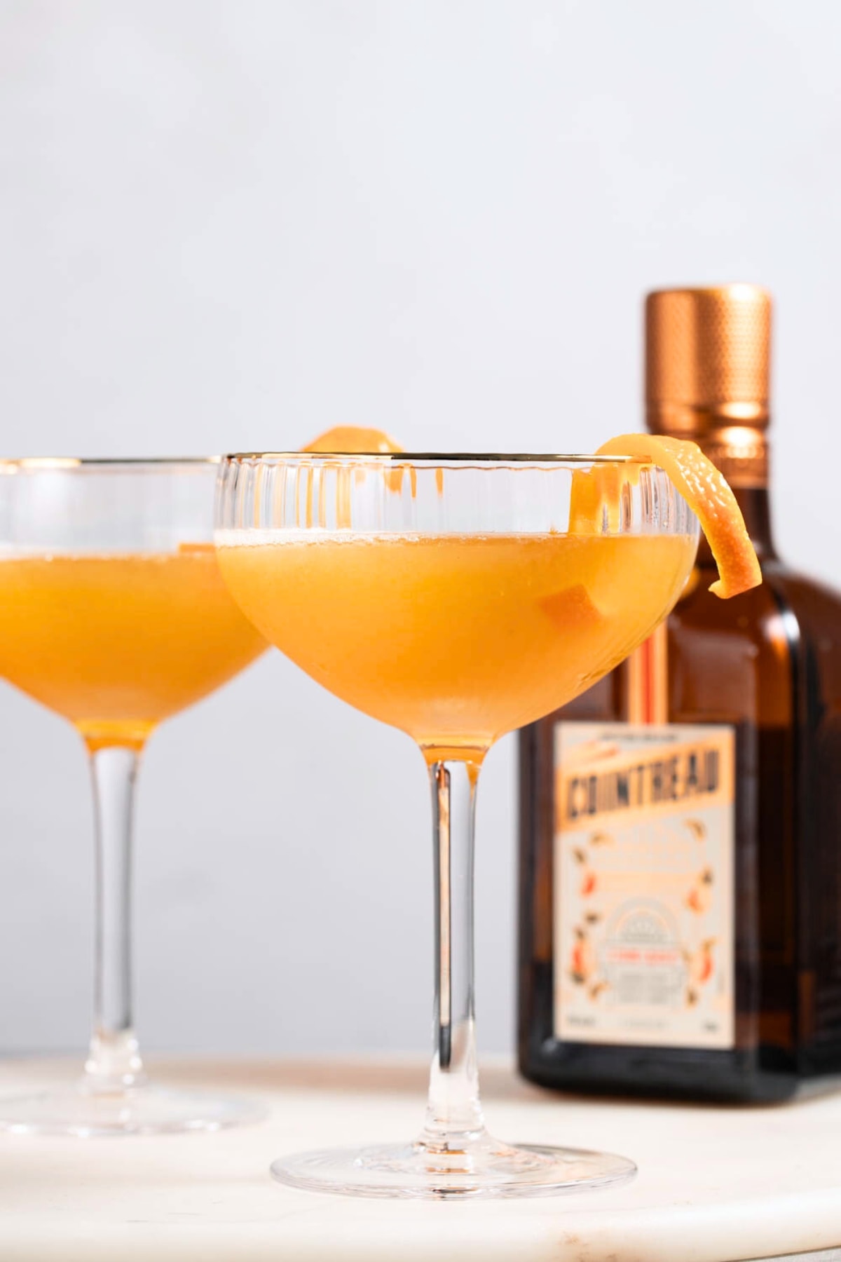 Two glasses of sidecar cocktail garnished with orange peel