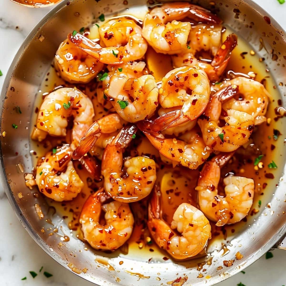 Shrimp tossed in a pan with honey garlic sauce.