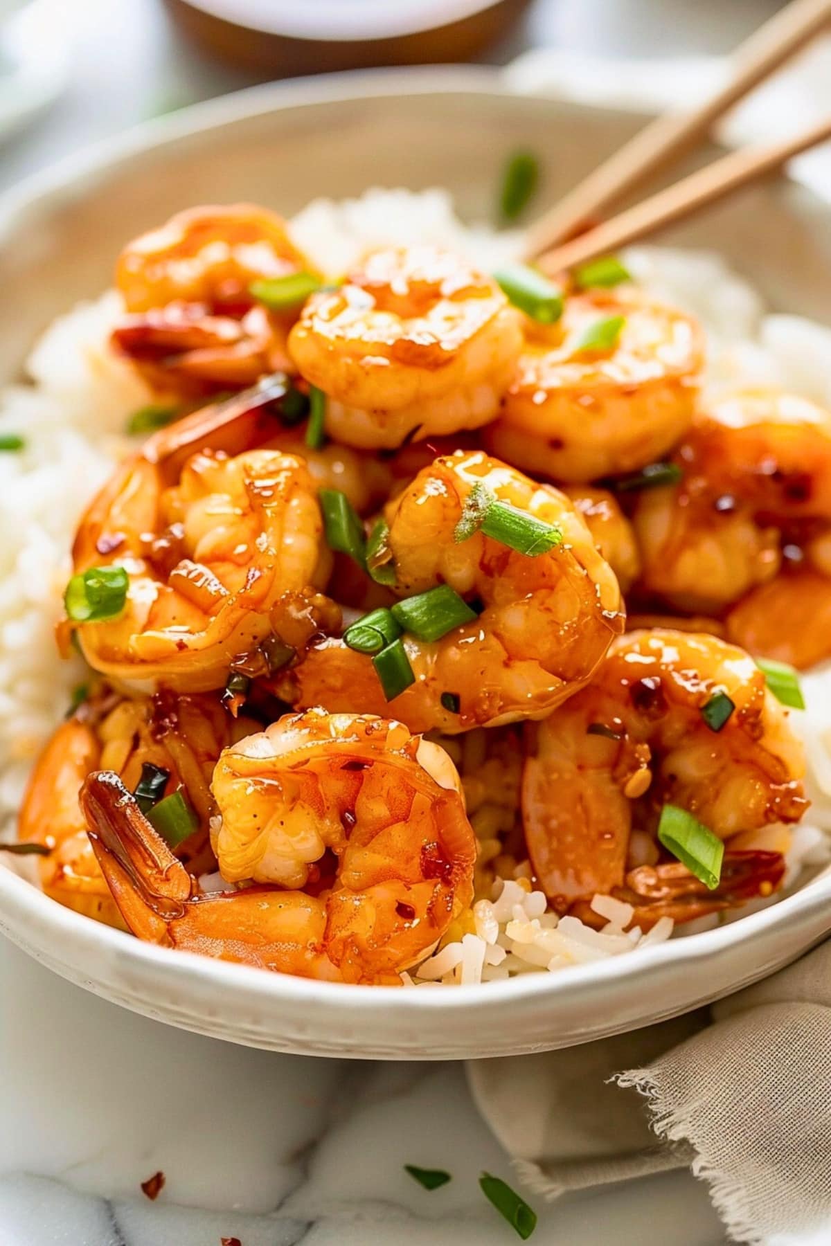 Honey garlic shrimp served on top of white rice in a bowl.