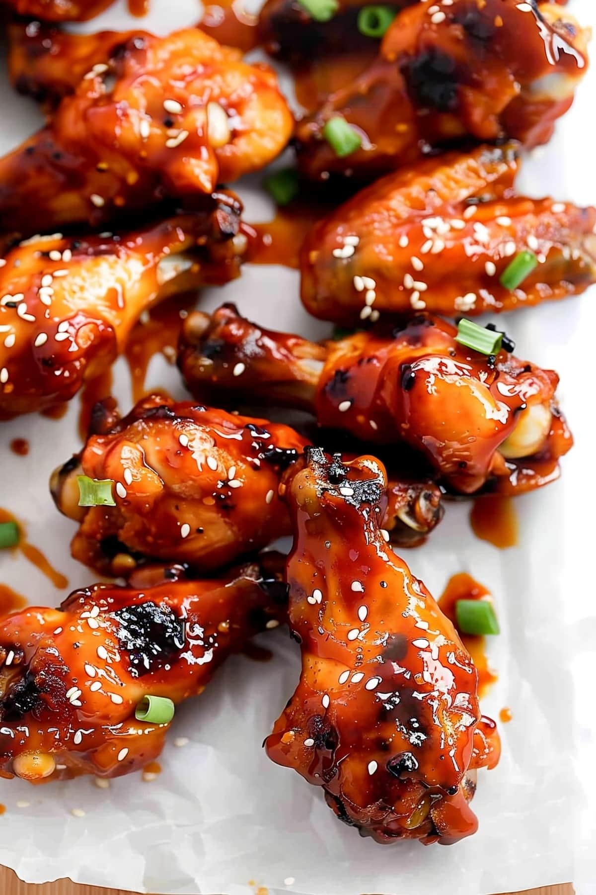 Close-up shot of Korean chicken wings with spicy sauce, sesame seeds and green onions