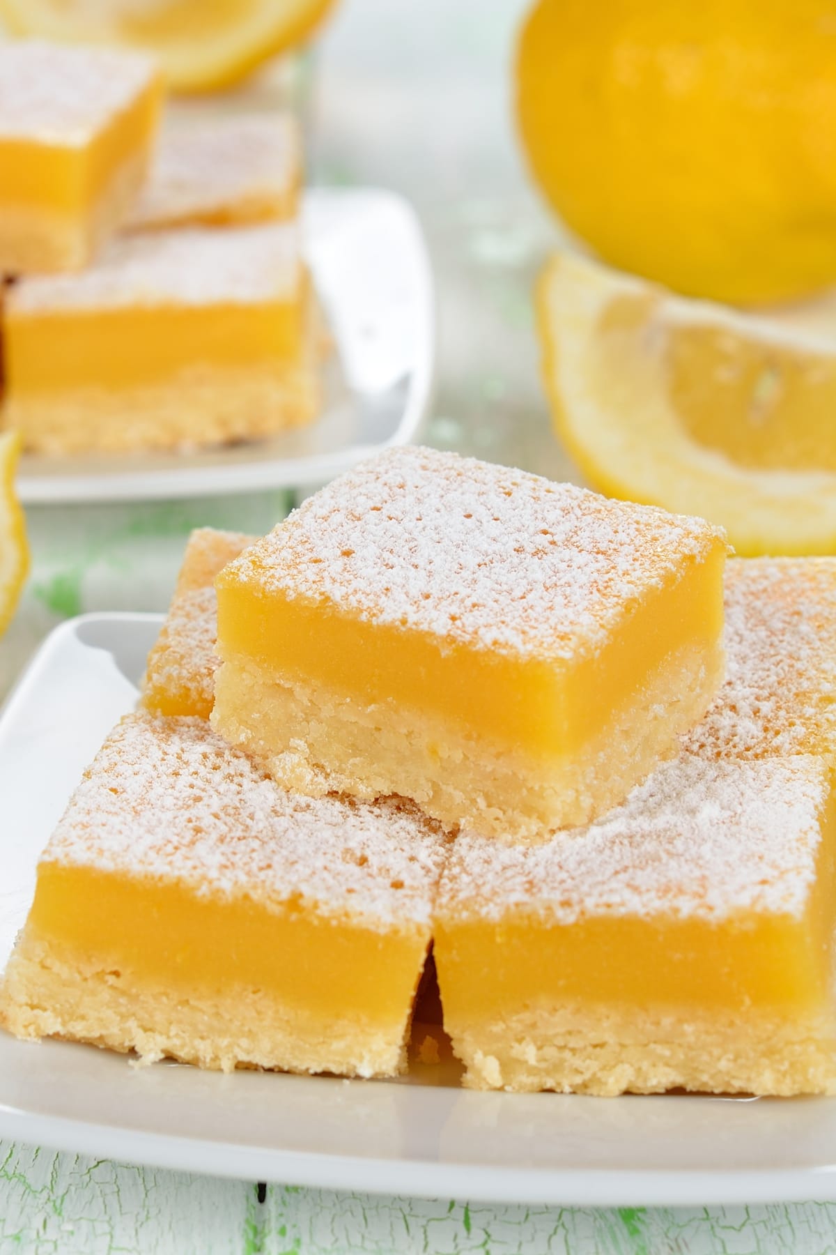 Lemon bars served in a square plate with powdered sugar on top.