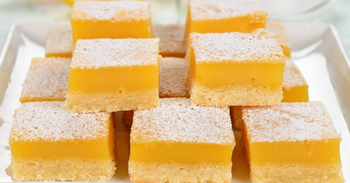 Lemon bars evenly cut in square served on a white plate.