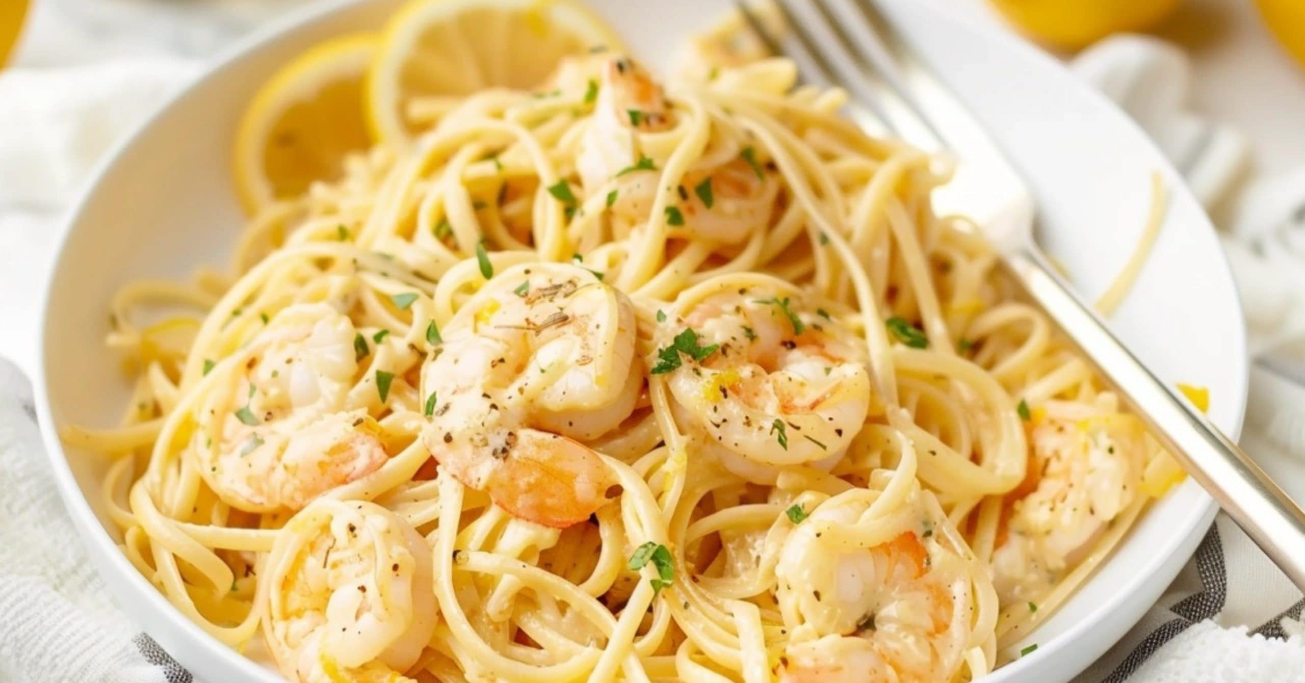Pasta with shrimp garnished with chopped parsley on a white plate.