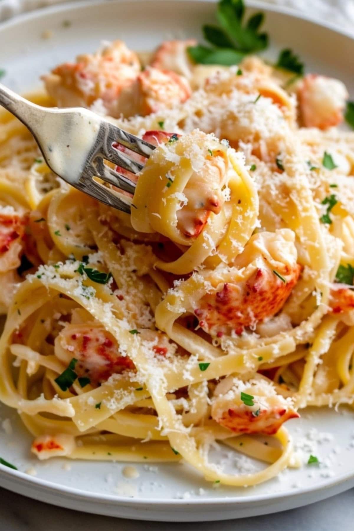 Fork picking creamy lobster pasta with cheese on plate.