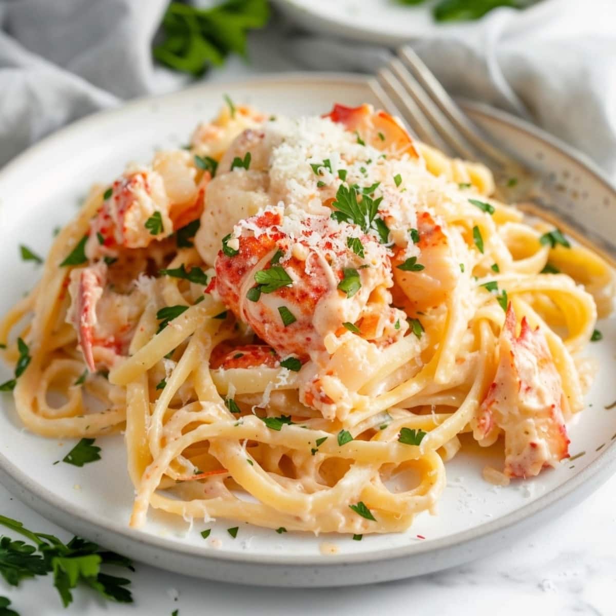 Pasta served with creamy sauce and lobster on a plate.