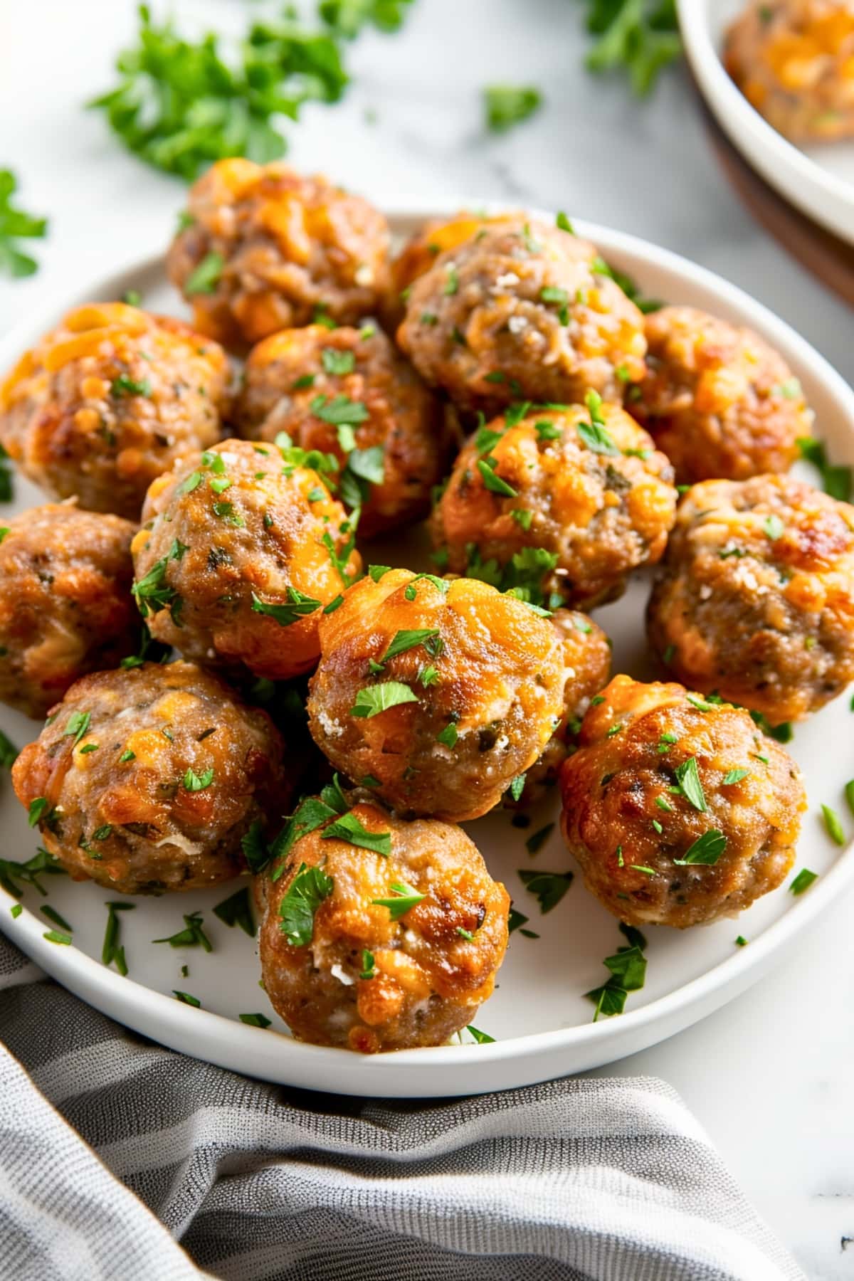 Bunch of sausage balls in a plate garnished with chopped parsley.