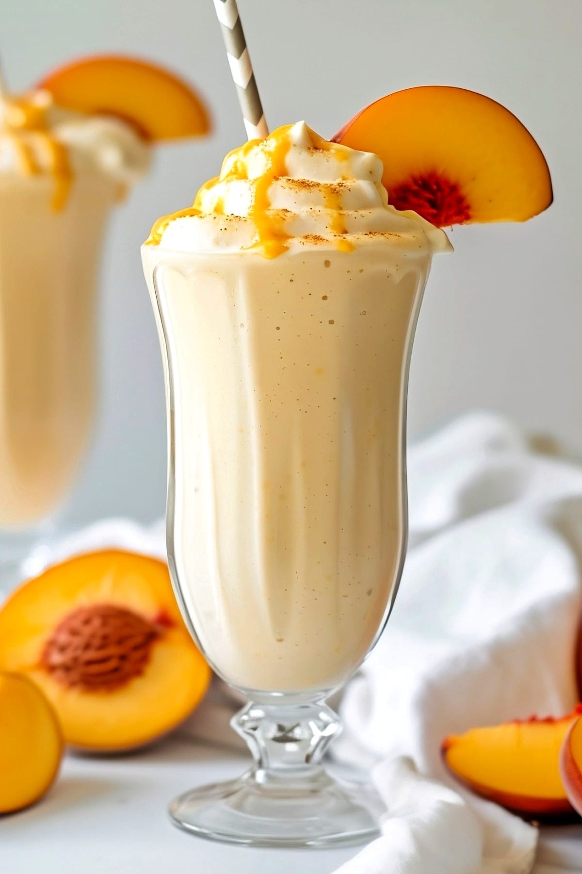 Copycat Chick-fil-A Peach Milkshake in a glass with whipped cream and fresh peach slice