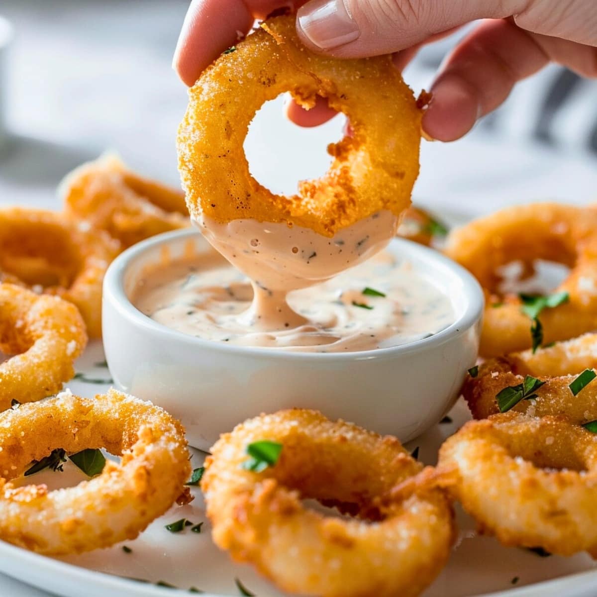 Plate of onion rings with a bowl of dipping sauce in the center.