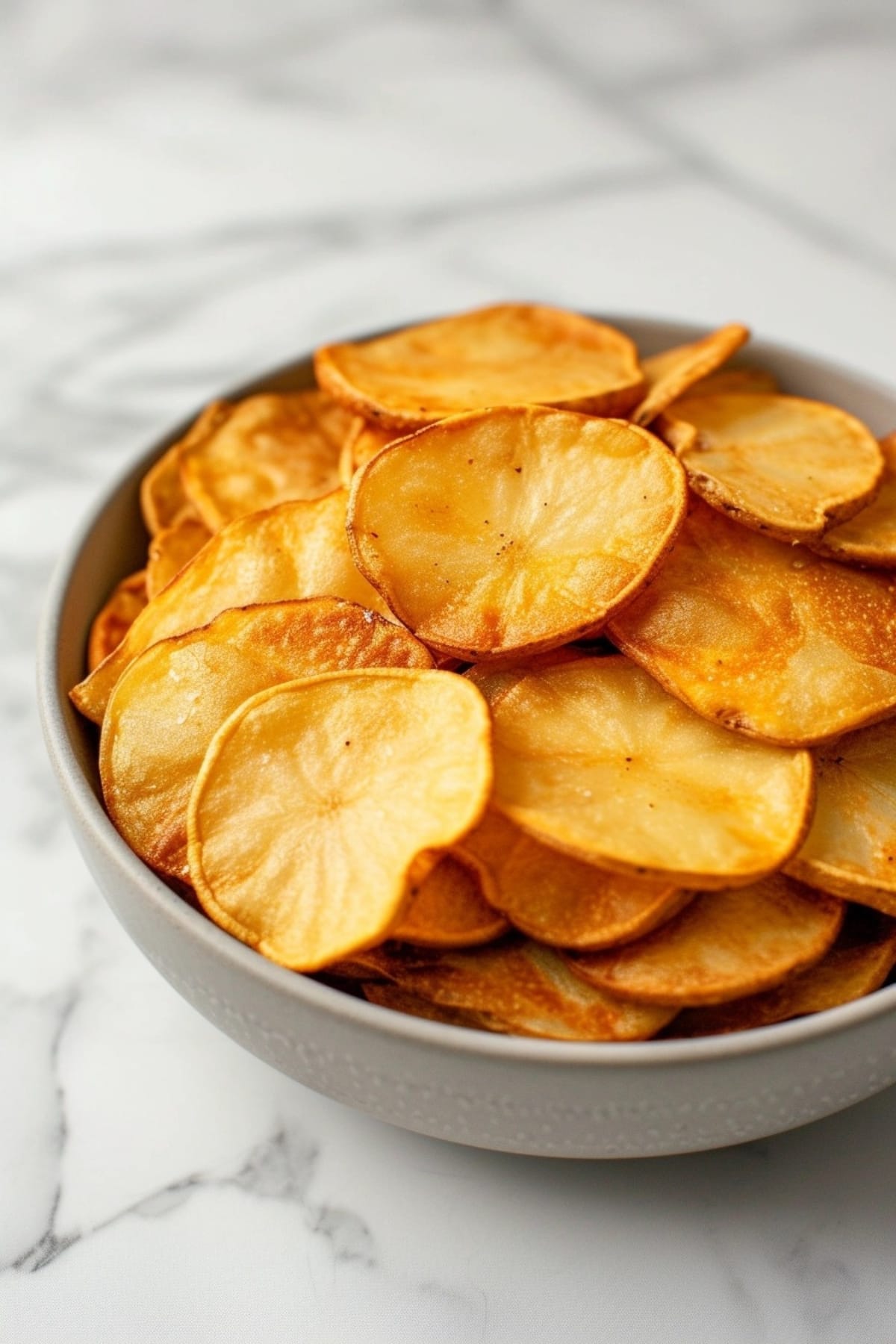 Potato chips in a white bowl.