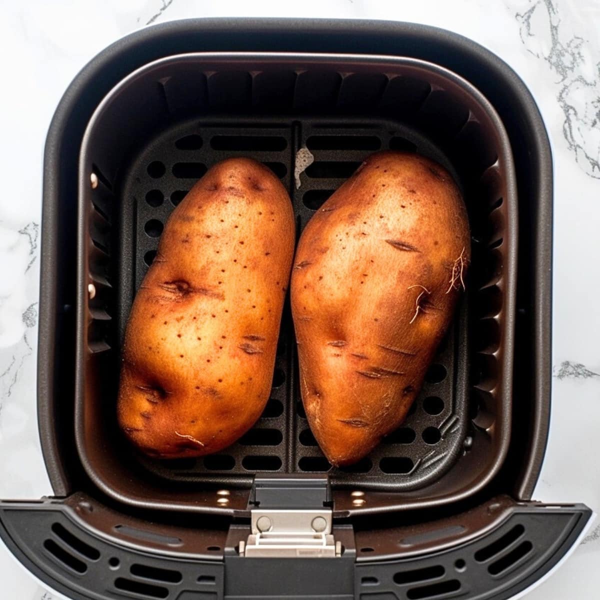 Raw sweet potatoes in air fryer basket