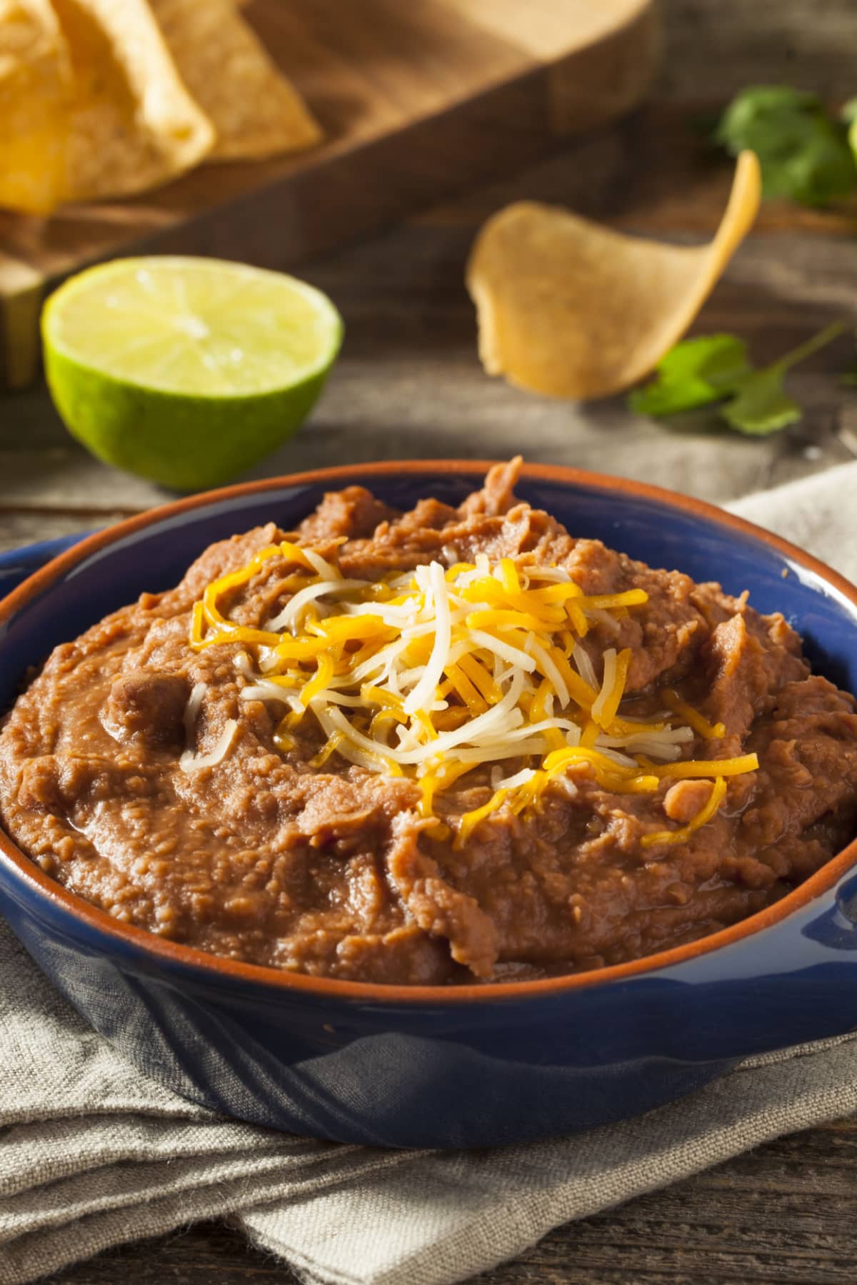 Refried beans in a blue pot topped with cheese.