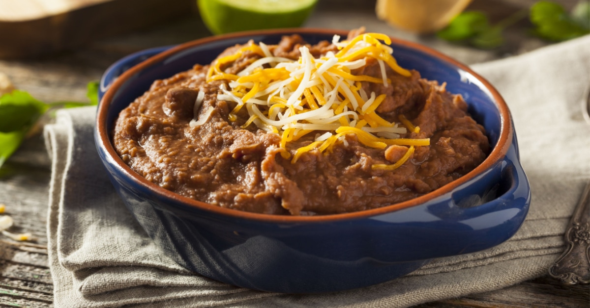 A bowl of refried beans topped with grated cheese.