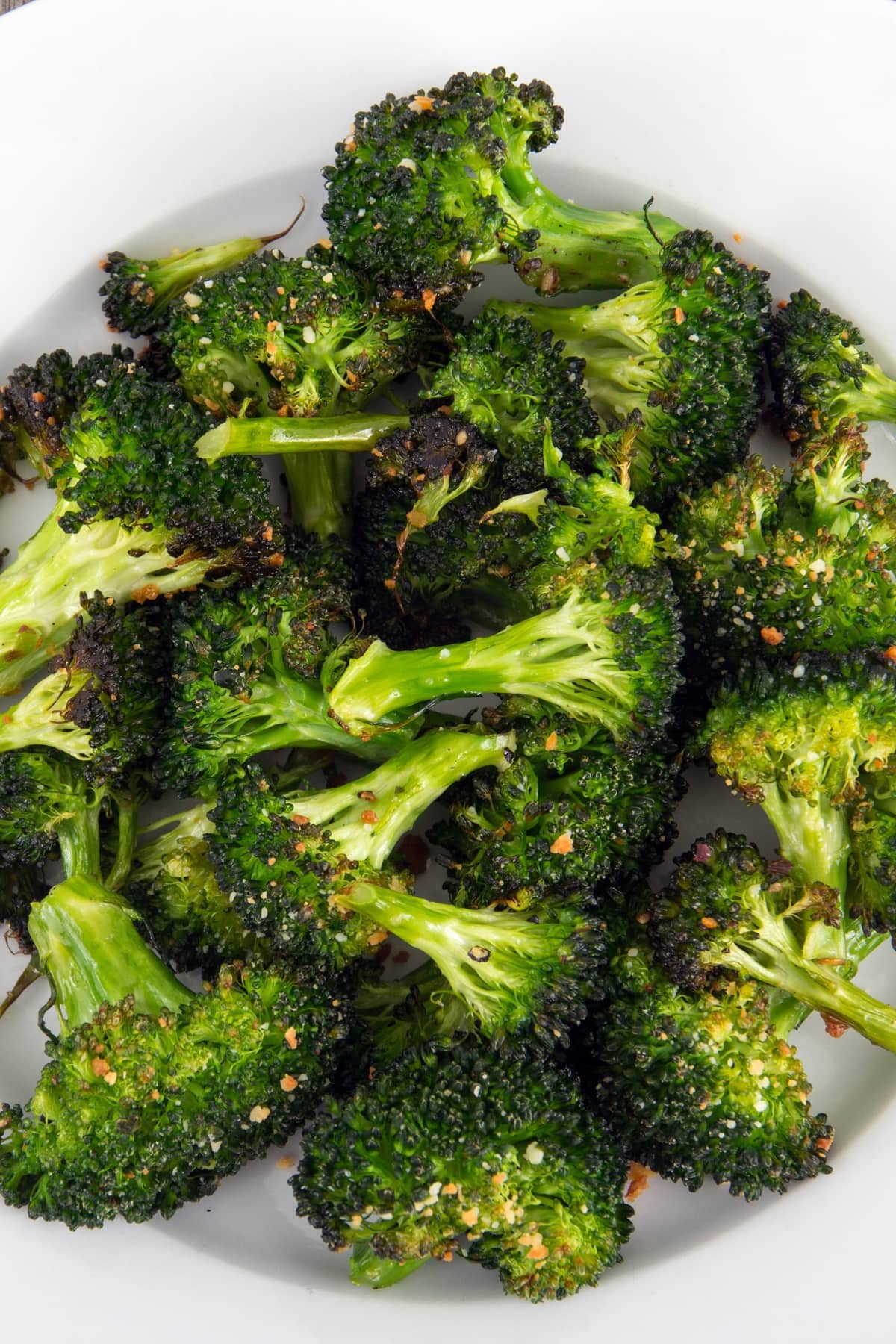 Roasted broccoli florets with parmesan cheese closeup in a plate.
