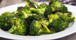 Roasted broccoli florets with parmesan cheese on a white plate.