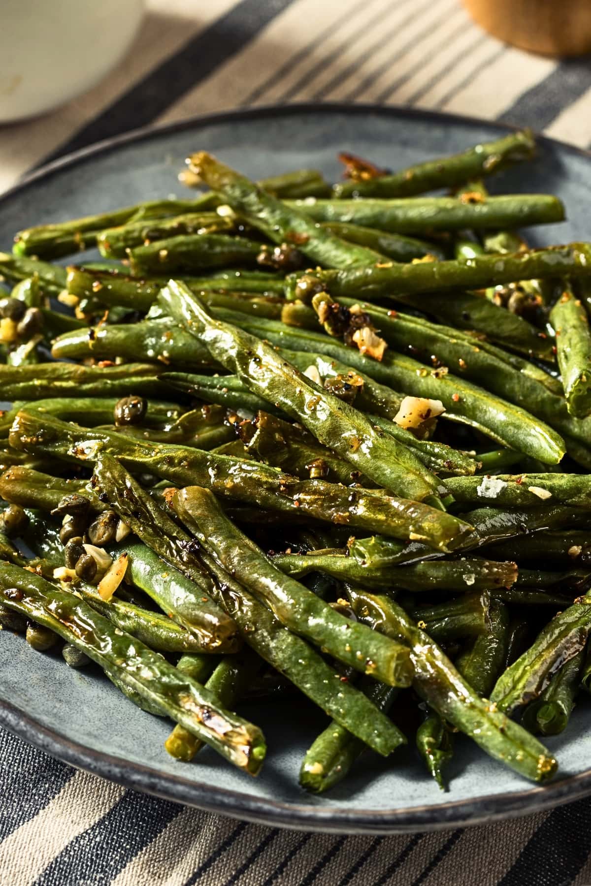 A serving of roasted green beans in garlic on a plate.