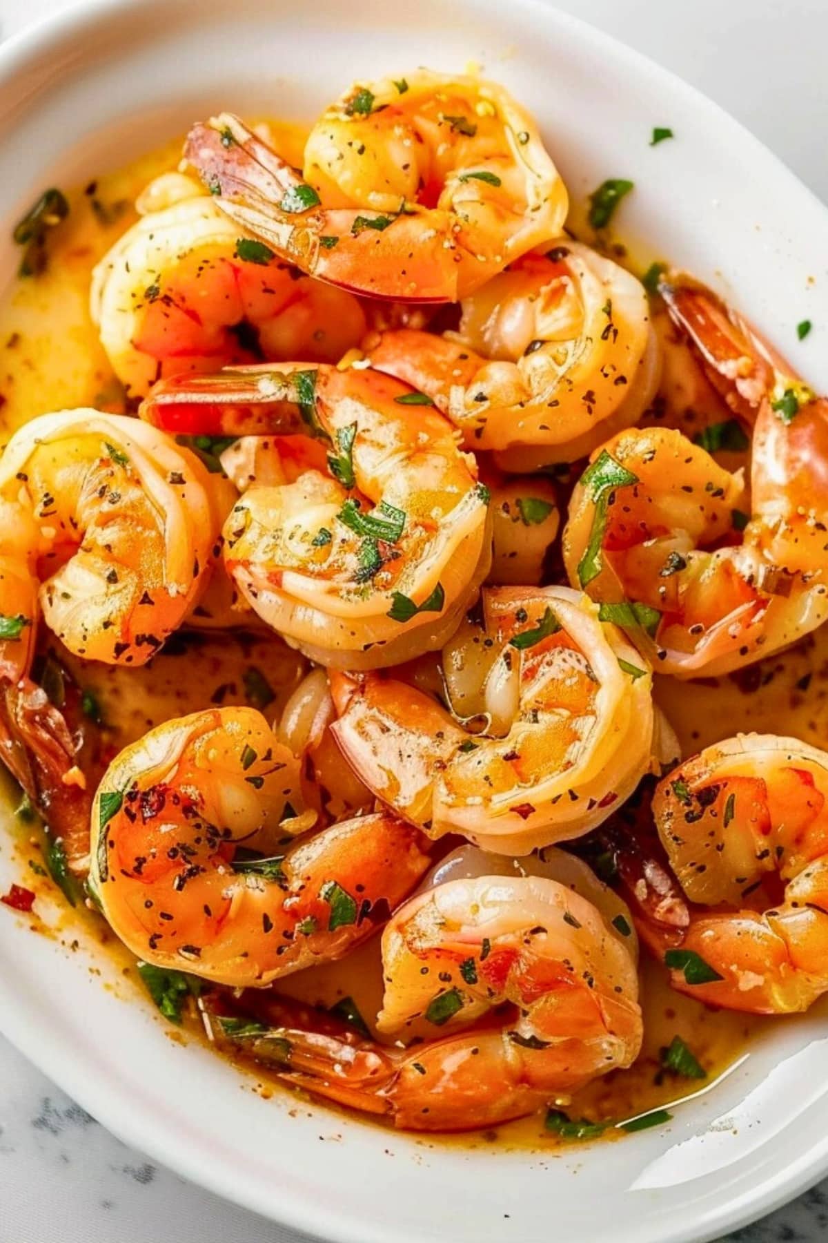 Shrimp with garlic butter sauce garnished with chopped parsley leaves.