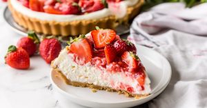 A slice of strawberry cheesecake in a white plate