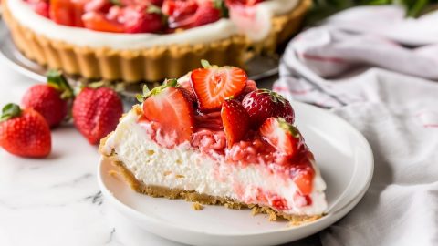 A slice of strawberry cheesecake in a white plate
