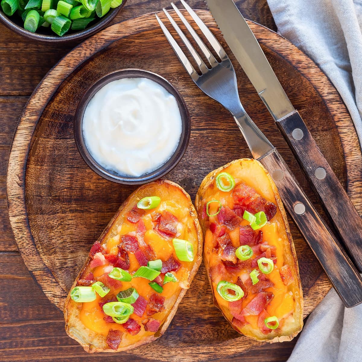 Potato skins served with sour cream garnished with chopped onions and bacon.