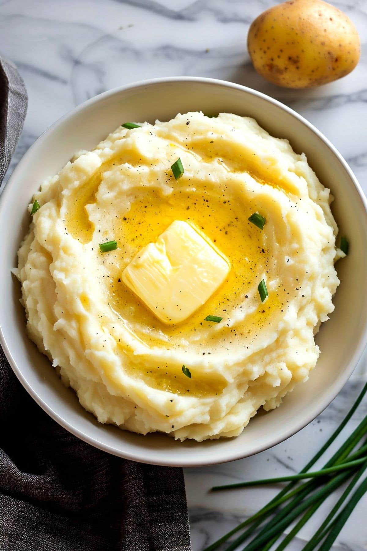 Mashed potatoes topped with melted butter and sprinkled with chives, creating a savory and flavorful side dish