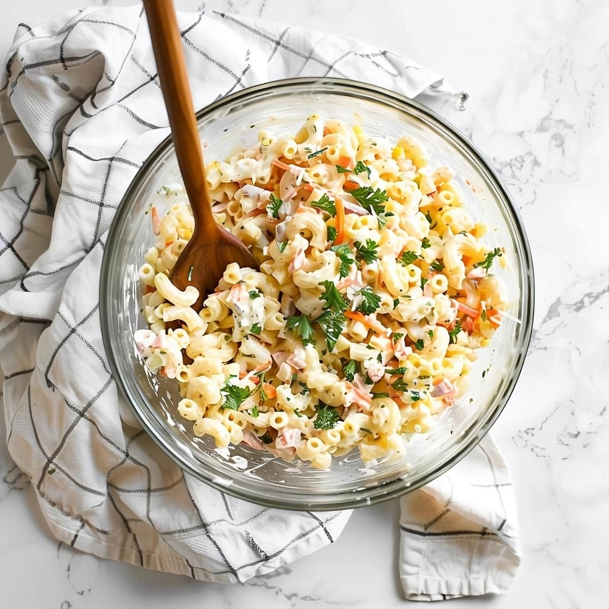 Macaroni salad tossed in a glass bowl.