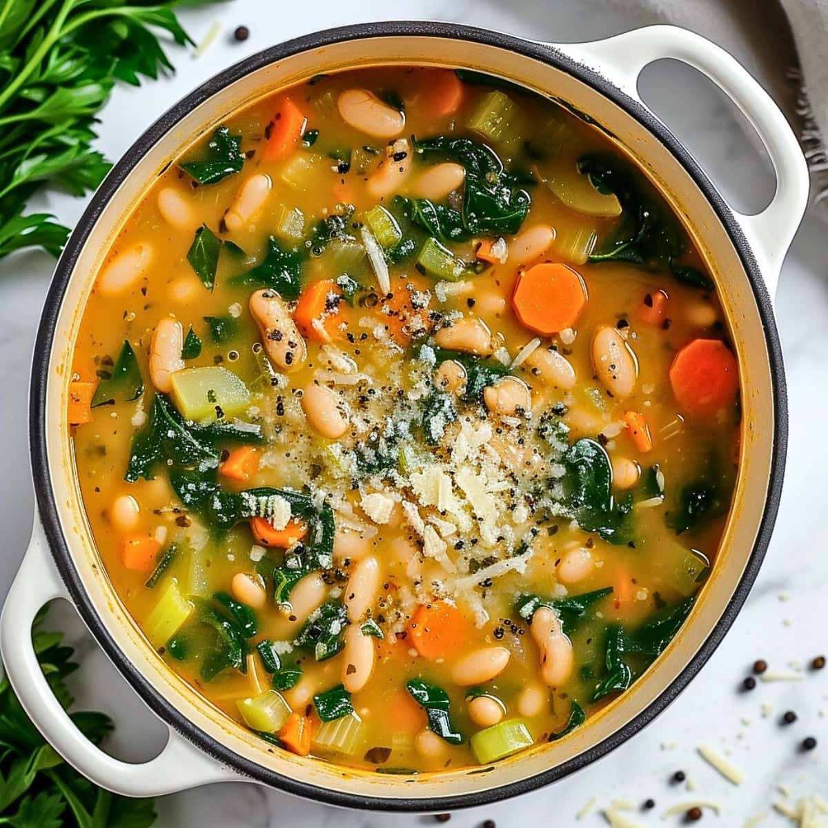 White bean soup with parmesan cheese and spinach on pot.